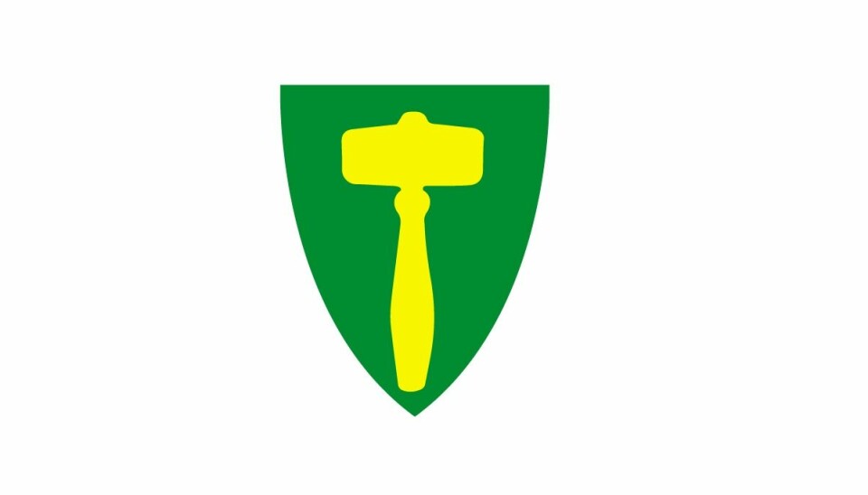 Rindal kommunes kommunevåpen. En gul ordførerklubbe på grønn bunn.