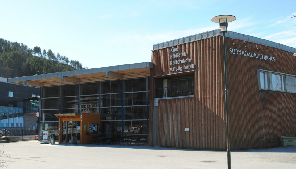 Bilde av et brunt bygg med store glassvinduer og på siden står det 'SURNADAL KULTURHUS'