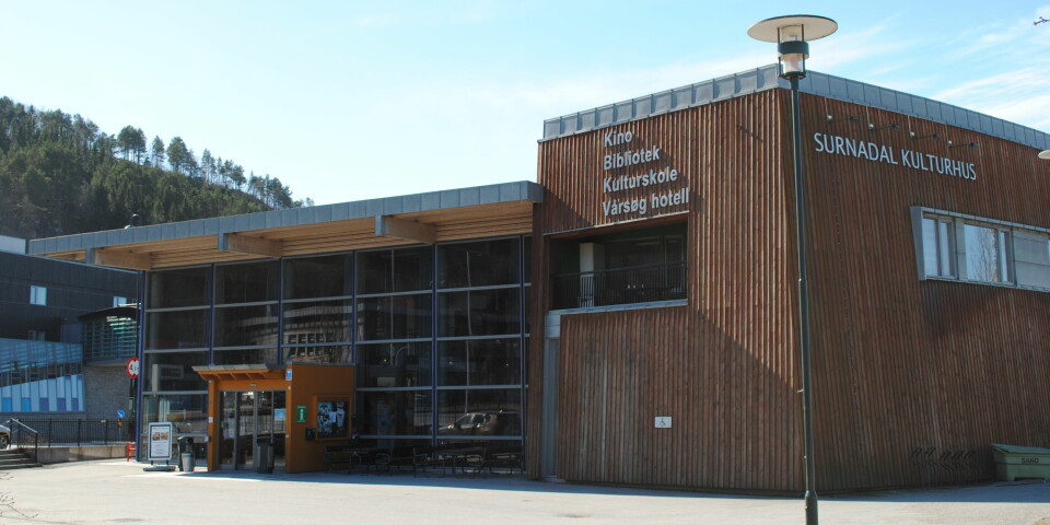 Bilde av et brunt bygg med store glassvinduer og på siden står det 'SURNADAL KULTURHUS'