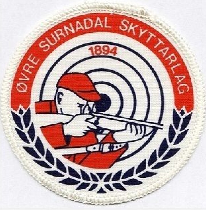 Oppskyting på Ellingmyra Et jakkemerke med en skytter som sikter med gevær og ei skyteskive. Teksten er Øvre Surnadal skytterlag.