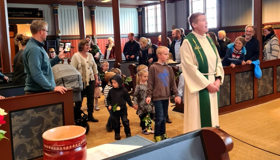 Sokneprest Lene Gåsvatn leda inngangsprosesjonen med barne som bar med blomster til alteret.