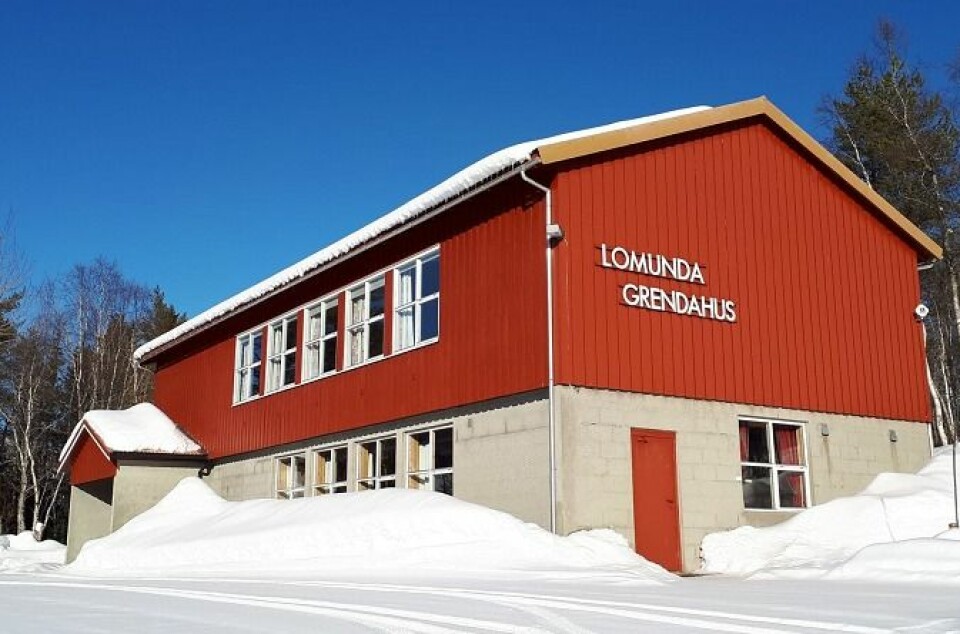 Ett rødt hus i to etasjer med snø rundt, og 'Lomunda grendahus' på veggen.