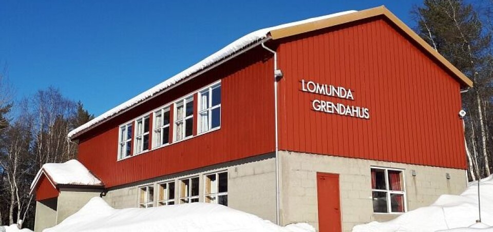Årsmøte Ett rødt hus i to etasjer med snø rundt, og 'Lomunda grendahus' på veggen.