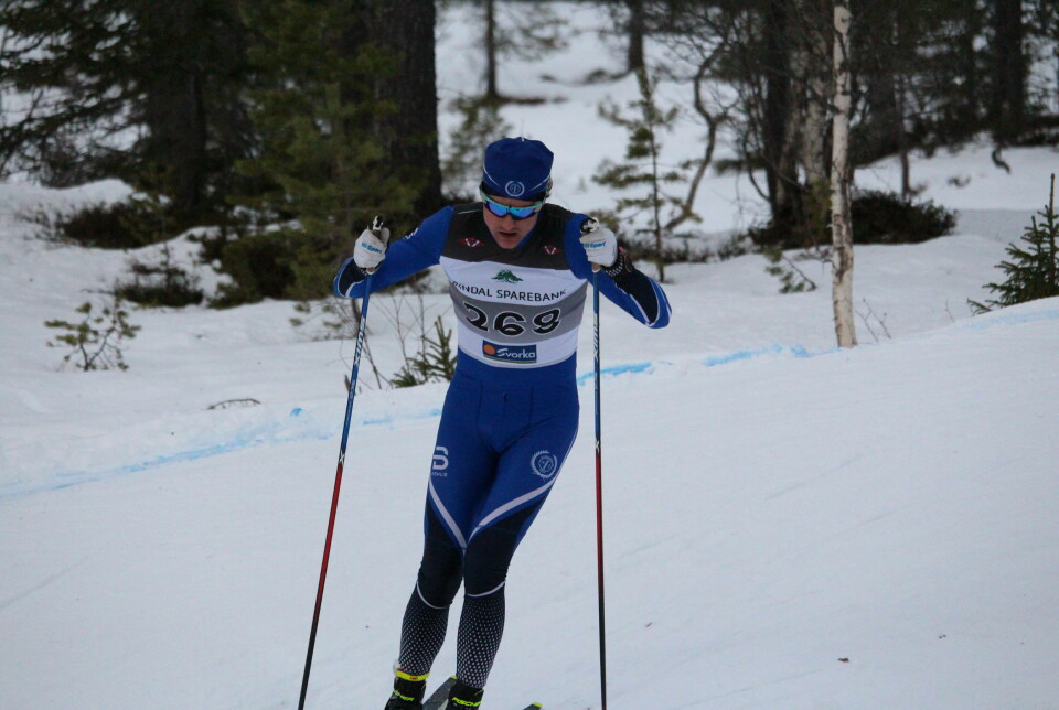 En mannlig skiløper i blå drakt i løypa med startnummer på brystet.