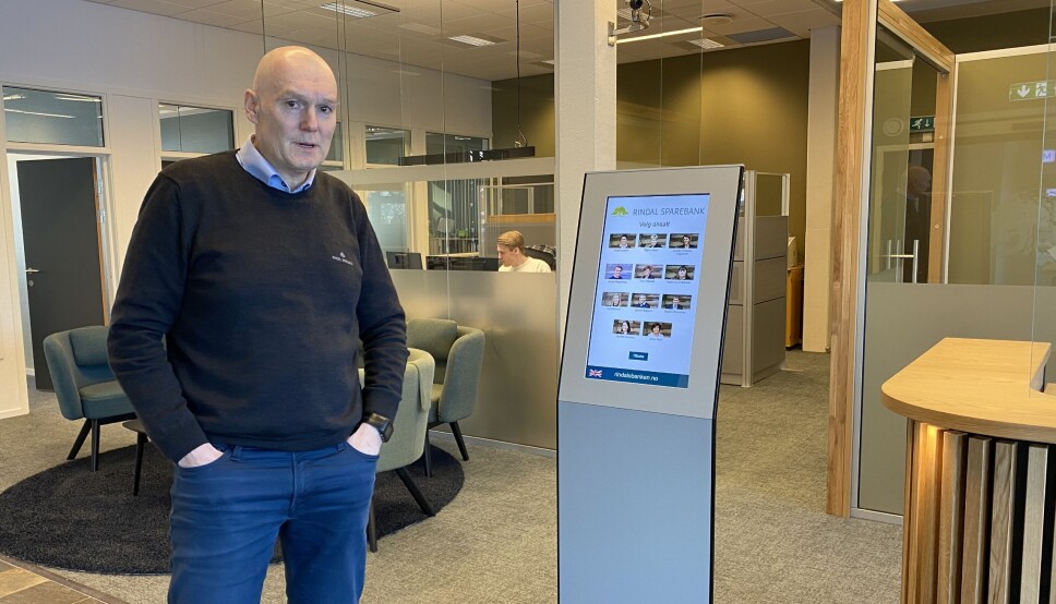 Banksjef Magne Bjørnstad ved det nye inngangspartiet. Her kan besøkende registrere seg på skjermen når de kommer.