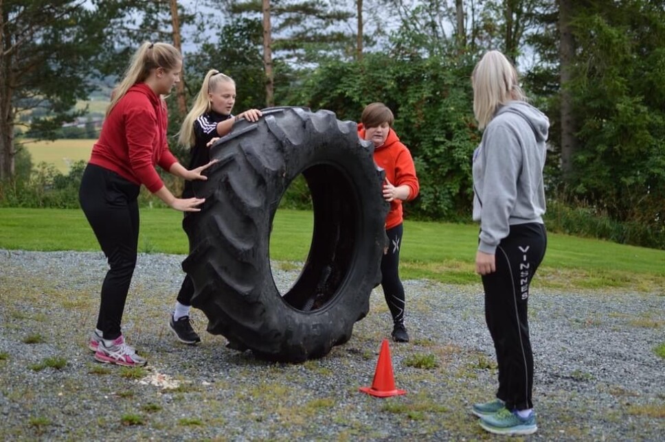 Bilde fra SkoFaden - en happening fra starten av skoleåret, da avdelingene gjennomfører forskjellige oppgaver. Her triller gruppa til Vanja et traktordekk gjennom ei løype markert med kjegler.
