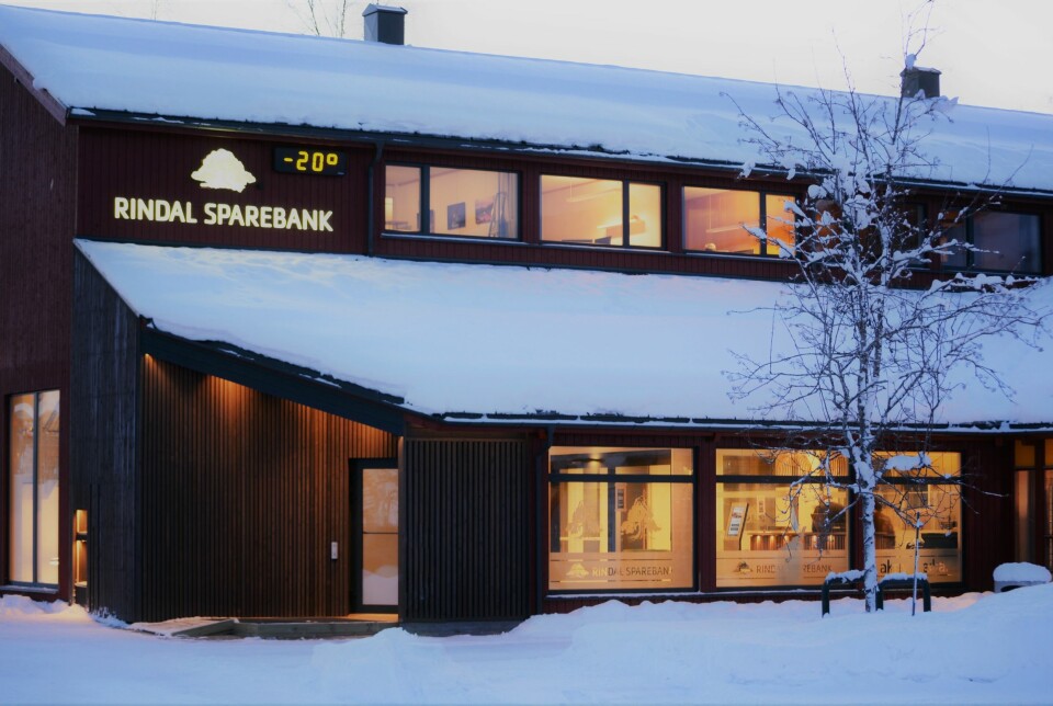 En bygning i to etasjer med snø på taket og logoen til Rindal Sparebank på veggen. Rindal Sparebank sine lokaler i Rindal.
