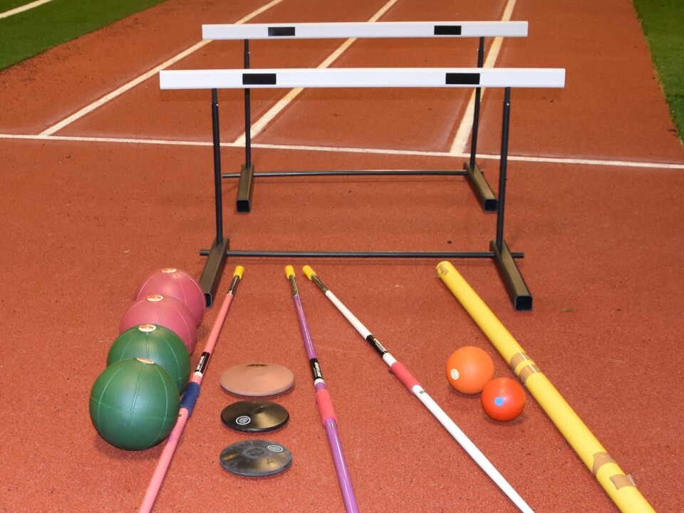 Utstyr for friidrettsøvelser på en løpebane inne i en hall.