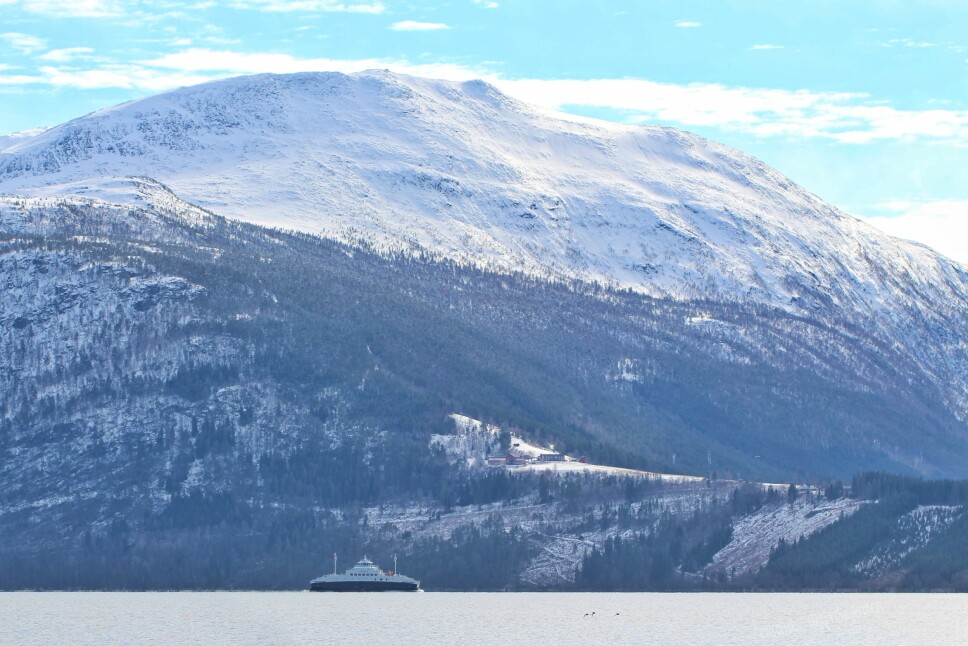 Utsikt fra Hunnes, ferja på vei ut fra Rykkjem. Gården Hals, Vardhaugen og Storhammaren i bakgrunnen.