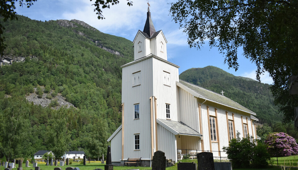Todalen kirke med gravstøtter foran og fjell i bakgrunnen