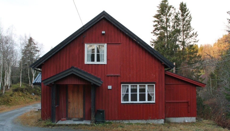 Et rødt trehus. Skog i bakgrunnen.