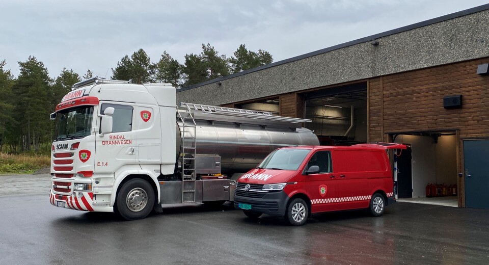 Rindal brannstasjon. En tankbil og en varebil med brannvesenets logo foran en brannstasjon.