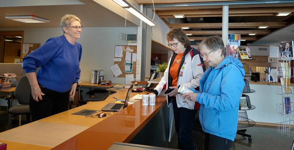Kjellaug Foseide og Inger Kjelås henter sine fjelltrimmenkrus på biblioteket hos Kari Mette Skjølsvold, som er daglig leder på Rindalshuset.
