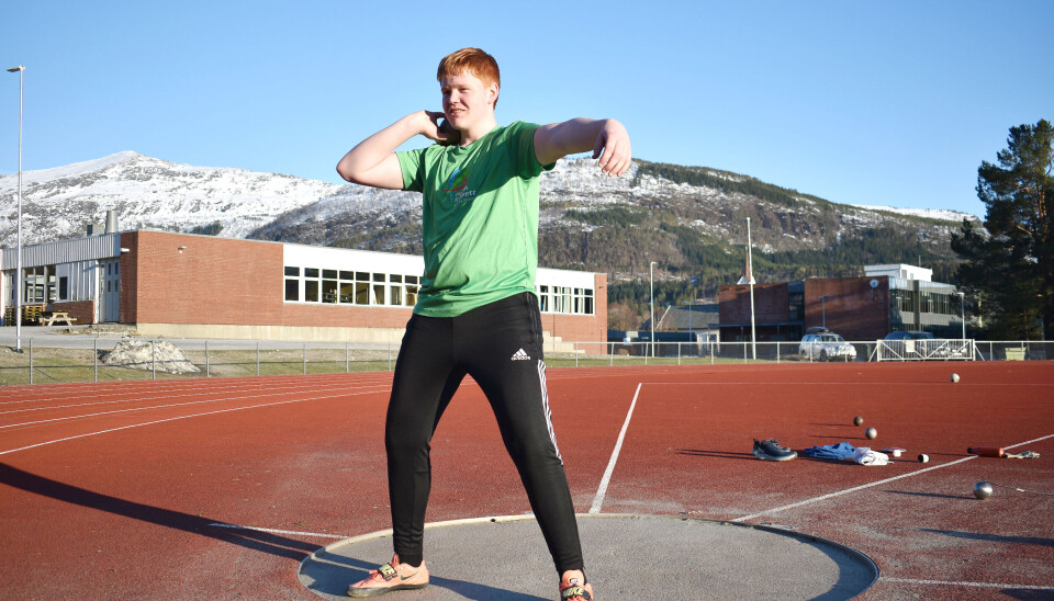 Sigve Holten. En ung gutt, tenåring, som trener på kulestøt på en utendørs idrettsbane. Han står i ringen med kula over skuldra, klar til kast.