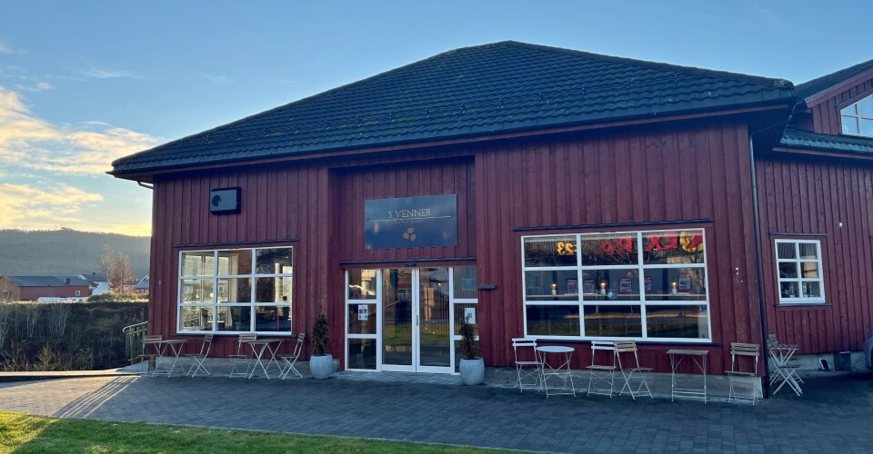 3 Venner Et hus der det er kafe. Bord og stoler utenfor.