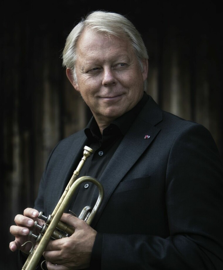 Ole Edvard Antonsen smiler og held ein trompet