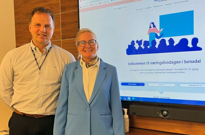 Allan Troelsen og Liv Dalsegg i Sparebank1 Nordmøre ønsker alle velkommen til Næringslivsdagen 22. mars. En mann og en kvinne som står foran en stor skjerm på en vegg. Dette er Allan Troelsen og Liv Dalsegg fra Sparebank1 Nordmøre. På skjermen er det informasjon om Næringslivsdagen i Surndal 2023.