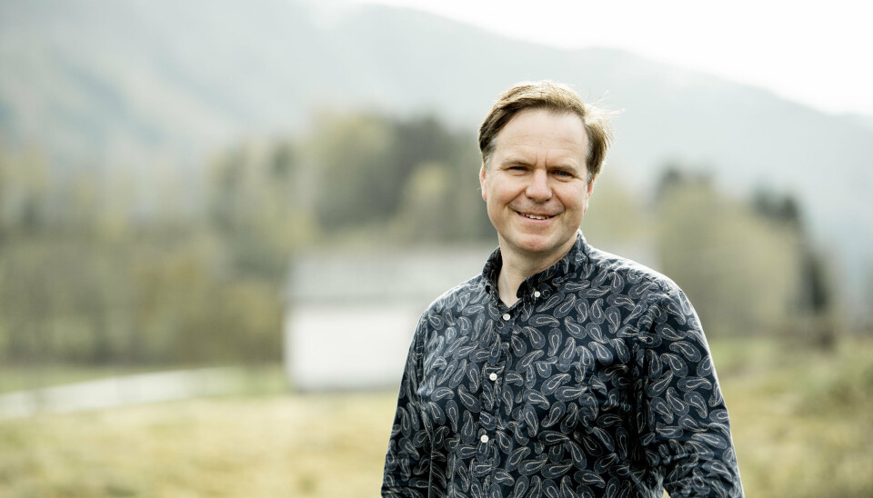 Alfred Bjørlo En mann som smiler. Diffust landskap i bakgrunnen