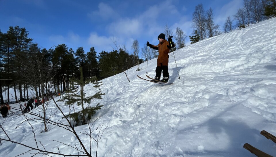 Et barn som hopper på ski i en kuleløype i en snødekt bakke.