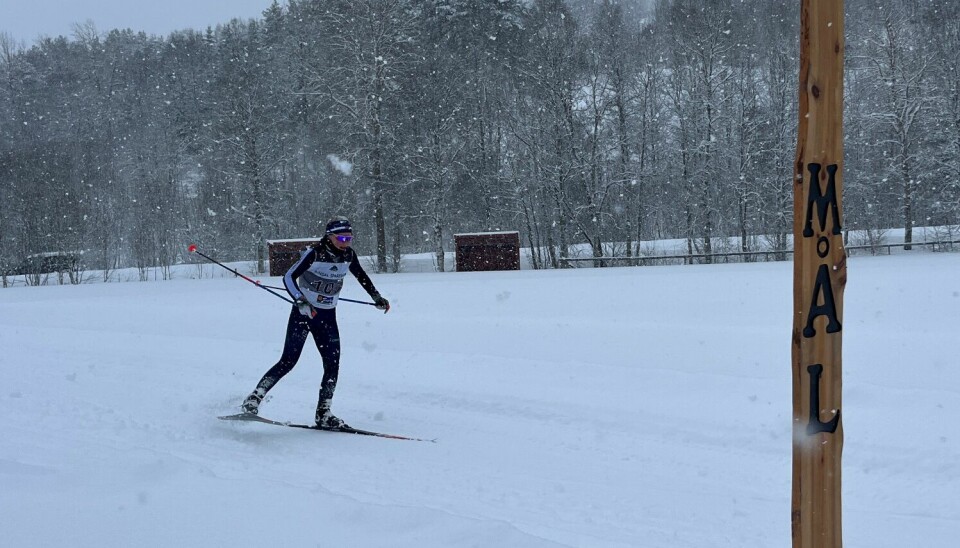 En kvinnelig skiløper mot mål i et skirenn. Det snør.