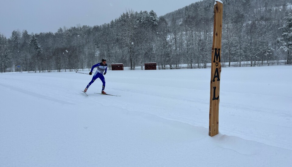 En mannlig skiløper mot mål i et skirenn.