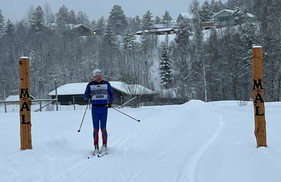 En mannlig skiløper som passerer målstreken i et skirenn.