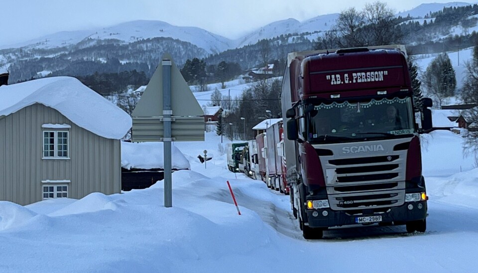 En kø med lastebiler på snødekt veg.