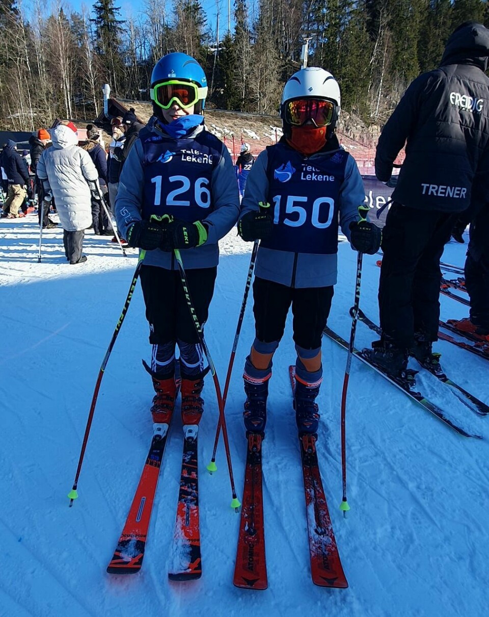 To gutter i alpinutsyr ved siden av hverandre på en skiarena