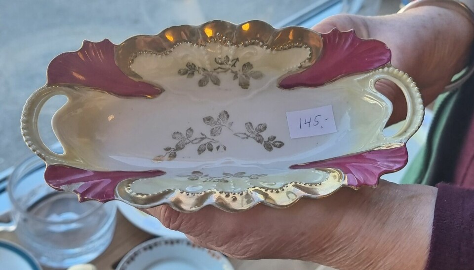 En pent hvitt porselensfat med rosa og gulldetaljer og blomster. En prislapp hvor det står 145 kroner.