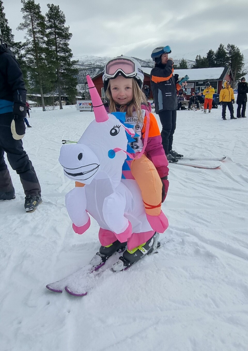 En liten jente med slalomhjelm og briller på hodet er kledd ut som en enhjørning.
