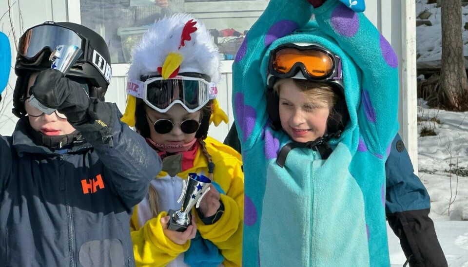 3 barn med kostyme holder pokaler over hodet