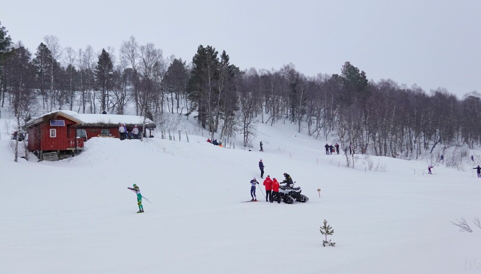 Skiløper i grønn trikot staker i tet, mens skiløper på andreplass senker farten for å ta litt saft. Den røde Tørsåsløa i bakgrunnen.