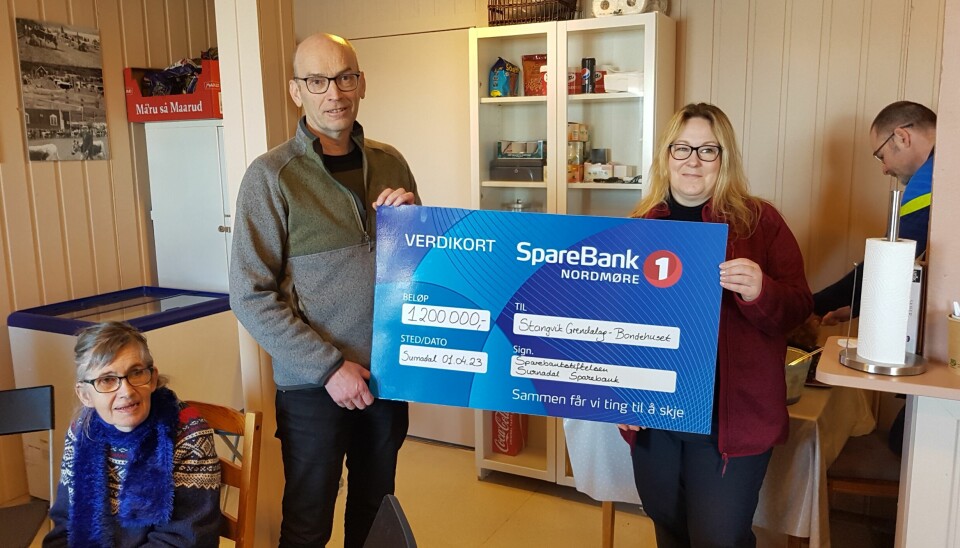 En mann og en kvinne holder en stor blå sjekk fra Sparebank 1 mellom seg
