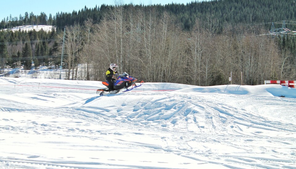 En liten unge hopper på snøscooter