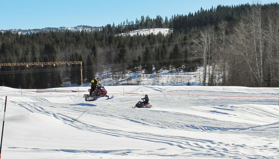 Barn som kjører snøscooter på bane.