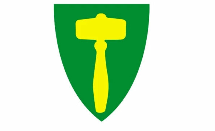 Kommunevåpenet til Rindal kommune. Ei gul ordførerklubbe på grønn bunn.