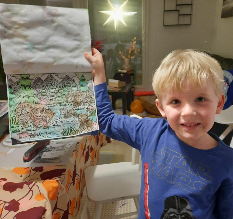 En gutt holder opp et bilde han har fargelagt