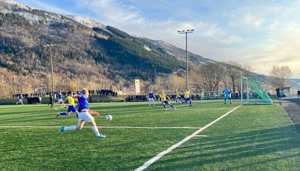 Fotballkamp hvor en blå spiller jager ballen