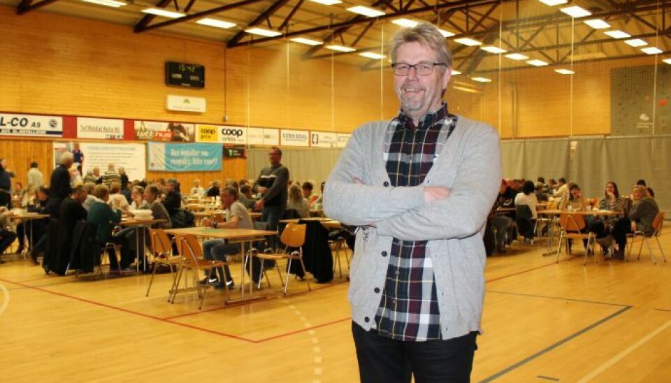 Oddbjrøn Heggem (Sildballfestivalen 2016) En mann som står i en idrettshall. Bak han er det satt ut bord og stoler der folk sitter og spiser.