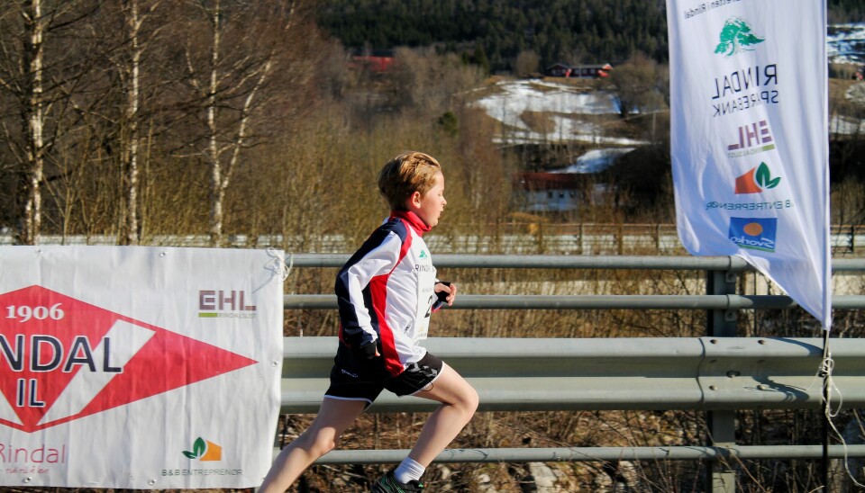 En liten gutt løper foran Rindal IL banner