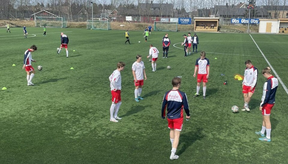 Rindal gjør seg klar til kamp mot Tiller 2 Et herrelag i fotball står på banen og sparker ball til hverandre før kamp