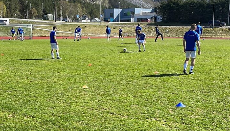 Spillerne gjør seg klare til bortekamp Spillere i blådrakter står på en fotballbane og varmer opp før kamp