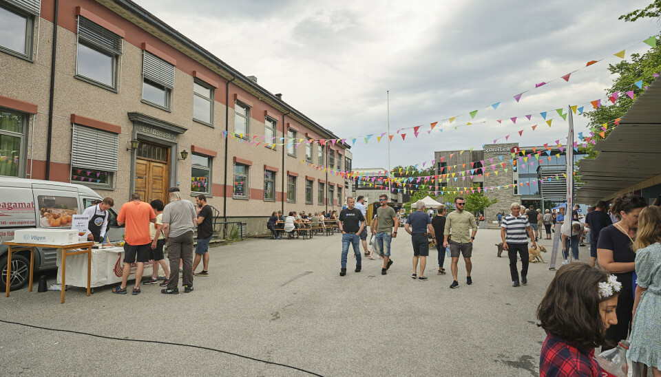 Mennesker går oppover en gate hvor det er flere stand og fargerike flagg henger over gata