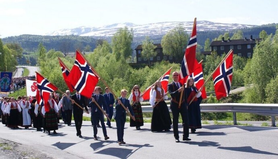 Mange barn og voksne går i barnetoget med store flagg