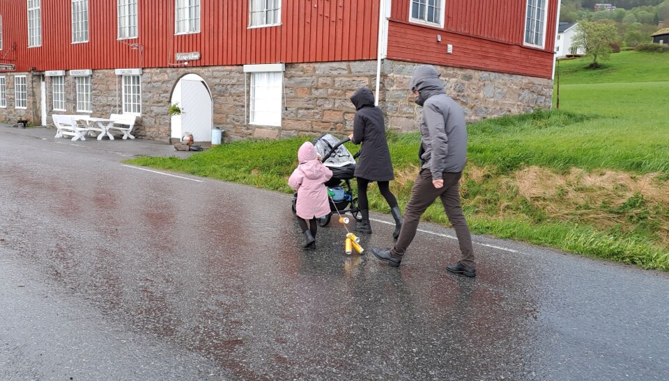 En familie går foran et rødt hus