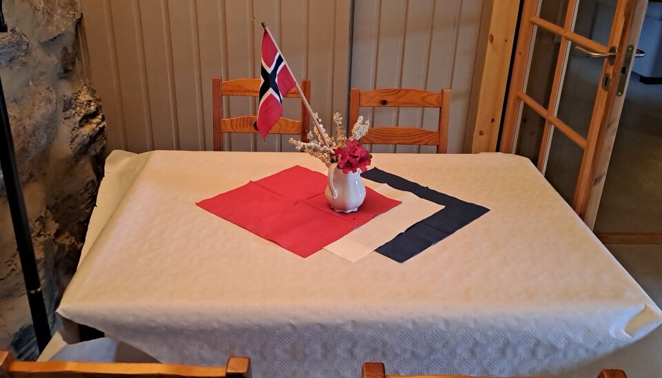 Et bord med hvit duk med rød, hvit og blå pynt med et norsk flagg