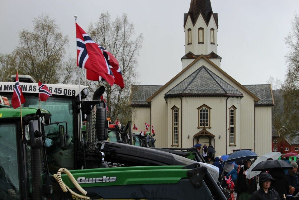 En grønn John Deere traktor med norskeflagg foran en hvit kirke