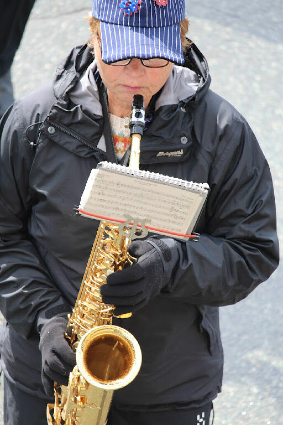 En kvinne spiller saksofon og ser på et noteark
