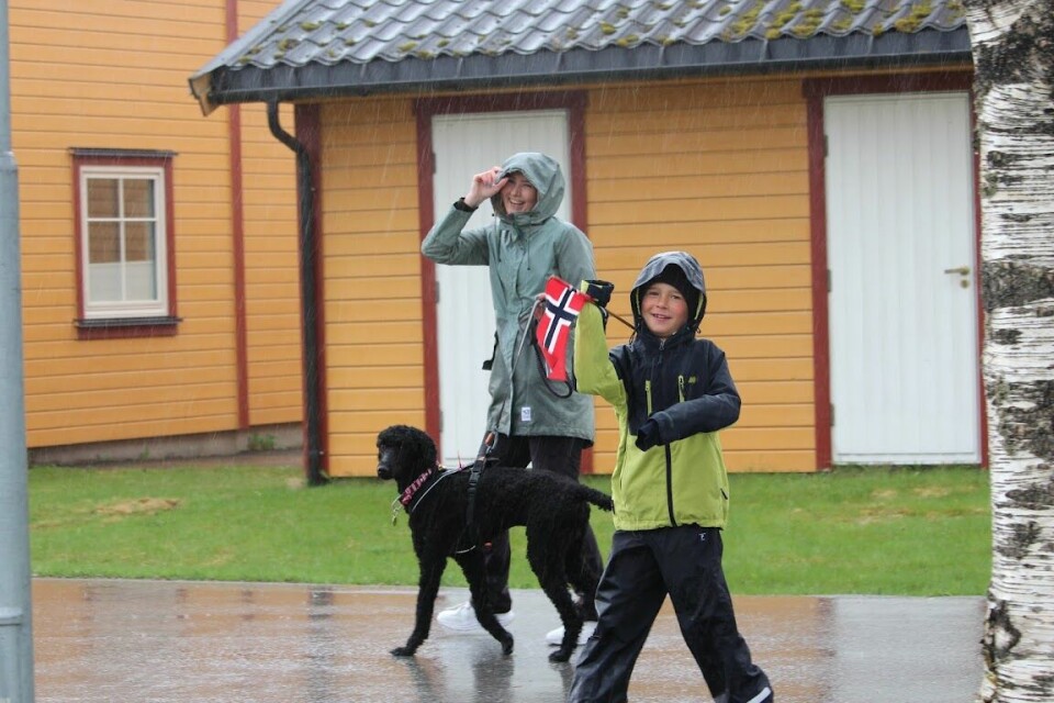 En mor og en sønn går med en hund i regnet og holder flagg