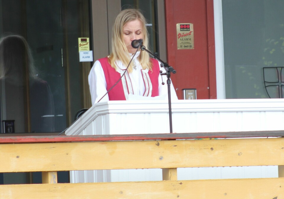 En kvinne i bunad snakker i mikrofon